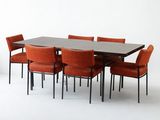 une table entourée de six chaises, avec un vase posé dessus