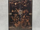une image représentant un meuble noir et doré orné d'oiseaux et de fleurs