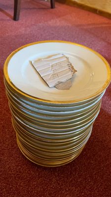 a stack of plates sitting on the floor in front of a chair