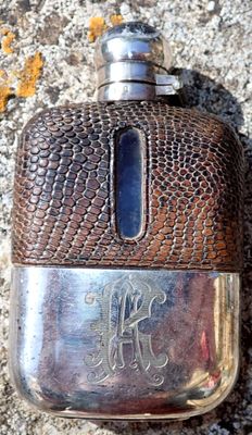 a silver flask with a monogram on it sitting on the ground
