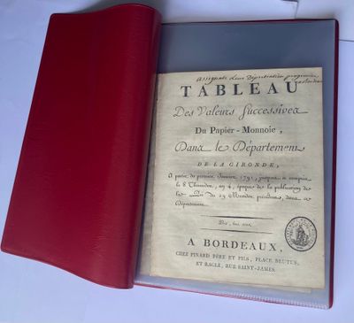 un livre rouge posé sur une table, à côté d'un stylo