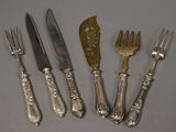 six fourchettes et couteaux en métal argenté sont alignés sur une table