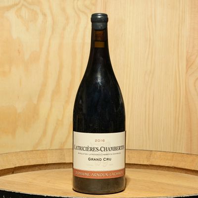 a bottle of wine sitting on top of a wooden barrel