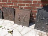 trois plaques en fonte posées sur le trottoir, à côté d'un mur de briques