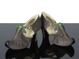 une paire de chaussures pour femme posée sur une surface réfléchissante, sur fond blanc