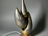 une sculpture en argent et en or posée sur un socle en bois