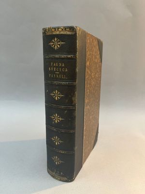 an old book sitting on top of a white table next to a white wall