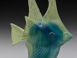 une figurine de poisson bleue et verte posée sur une table