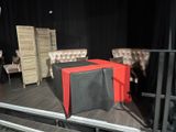 a table with a red table cloth on it in a stage setting