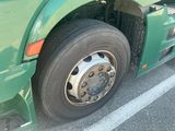 a green semi truck with a flat tire parked in a parking lot