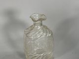 a clear glass bottle with a swirly design on it