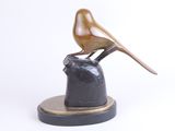 statue of a bird perched on a rock with a white background