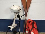 deux pagaies en bois à côté d'un moteur et d'un sac rouge