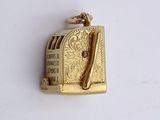 a gold charm that has a picture of a toaster and a knife on it