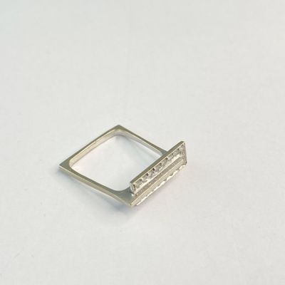 gros plan d'une bague en argent sur une surface blanche
