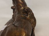 bronze statue of a man laying down on his back on a white surface