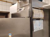 un réfrigérateur en acier inoxydable dans une cuisine, surmonté d'un panier