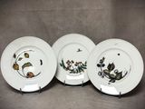 trois assiettes ornées de fleurs et de feuilles, posées sur une table