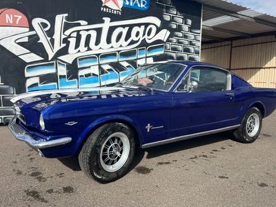 une photo d'une Mustang bleue garée devant un immeuble