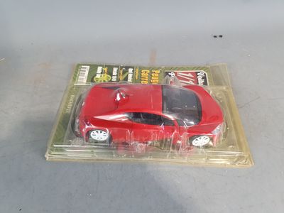 a red toy car in a plastic package on a table