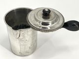 a silver coffee pot with a lid on a white table