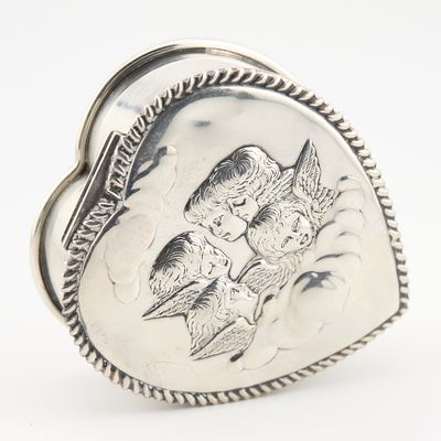 une image représentant une bague en argent en forme de cœur, sur laquelle figurent deux oiseaux