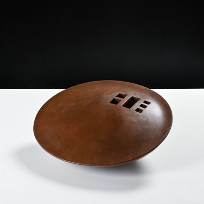 un ballon de football marron posé sur une table blanche, sur fond noir