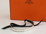 an orange box with a silver bracelet on it and a black ribbon