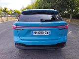the rear end of a blue car parked on the side of a road