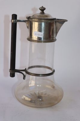 une cafetière en verre avec une poignée en métal posée sur une table