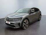 La voiture grise est garée dans une grande pièce au sol noir.