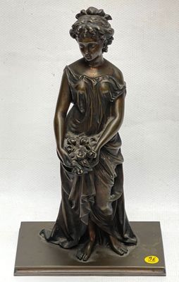 a bronze statue of a woman holding a basket of flowers