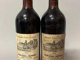 two bottles of red wine sitting next to each other on a table