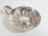 a silver bowl with a metal handle on a white surface