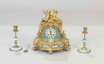 a gold clock sitting on top of a table next to two candles
