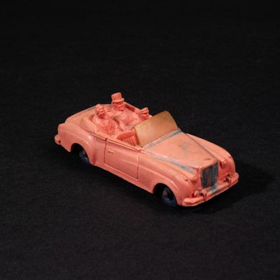 une petite voiture rose posée sur une surface noire