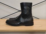 une paire de bottes en cuir noir posée sur une étagère en bois