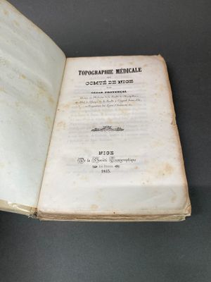 Quelqu'un tient un livre ouvert sur une table, sur fond noir.