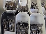 beaucoup de fourchettes et de cuillères dans des récipients posés sur la table