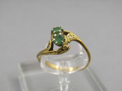 gros plan d'une bague en or avec une pierre verte