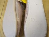pair of white slippers with yellow tags on them on a wooden floor