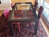 a glass table with red chairs and a rug on the floor