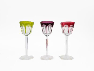 three different colored wine glasses sitting next to each other on a white surface