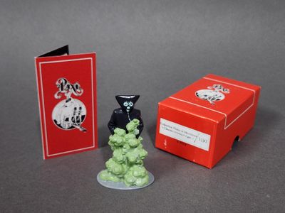 une petite figurine posée à côté d'une boîte rouge