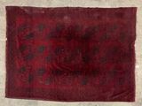 an old red rug with black and white designs on it
