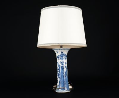 une lampe de table bleue et blanche surmontée d'un abat-jour blanc