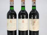 three bottles of red wine sitting next to each other on a white surface