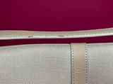 beige canvas and leather shoulder bag on a red background