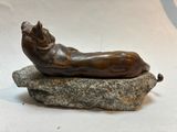 a bronze statue of a cat laying on a rock