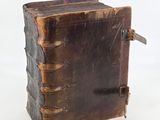 an old leather book sitting on top of a white surface